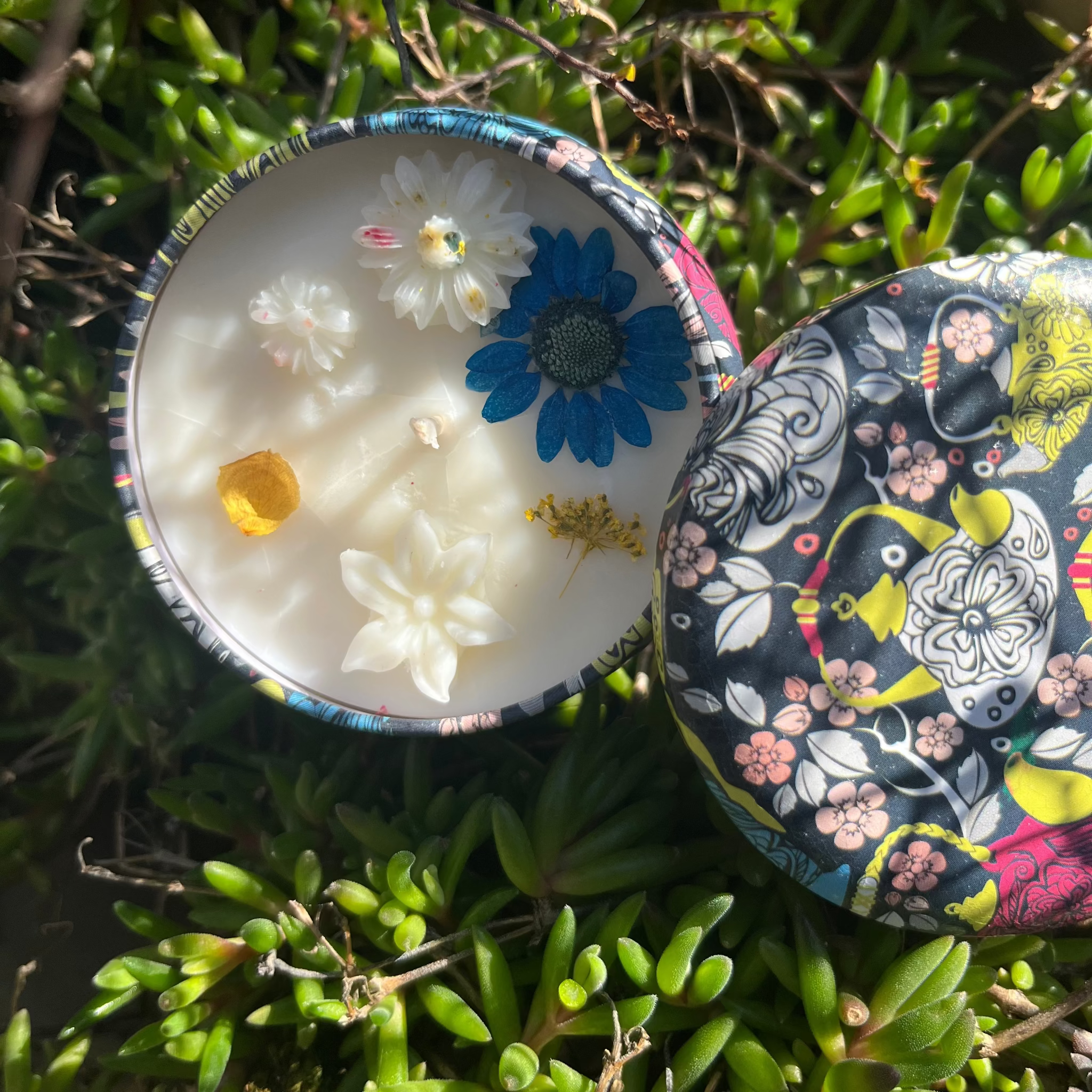 Geurloze kaars van kokos-raapzaadwas in zwart-geel-blauw blikje met bloemen