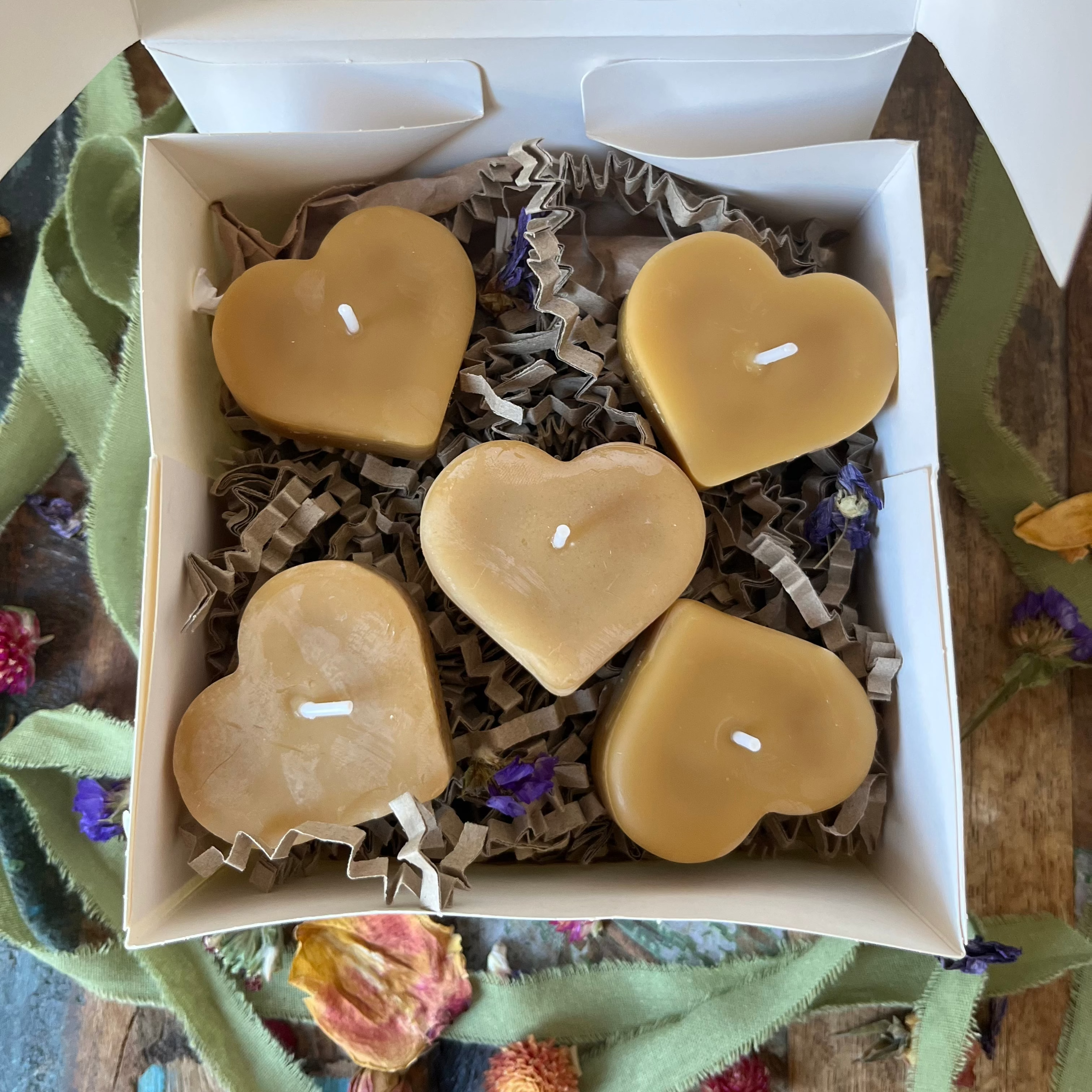 Set van vijf natuurlijke bijenwas theelichtjes in de vorm van een hart, gepresenteerd als een luxe geschenkset in een witte doos met droogbloemen.